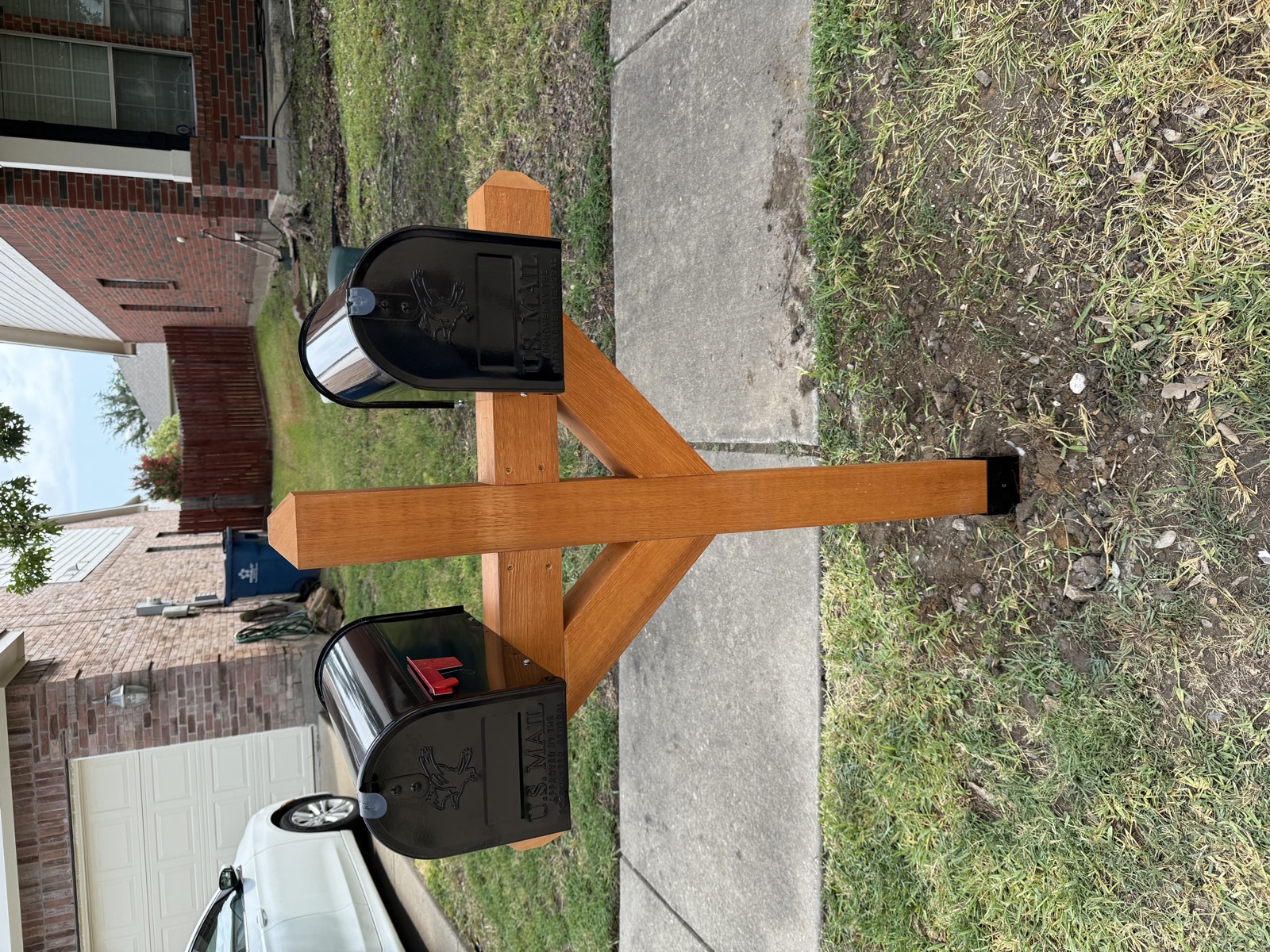 Custom cedar dual mailbox post with angled support arms installed at residential curb