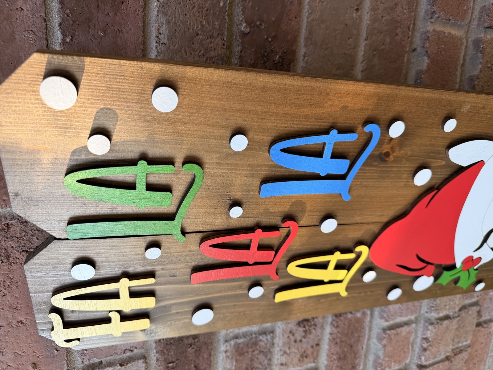 Close-up of Fa La La Christmas porch sign with colorful 3D letters on dark cedar